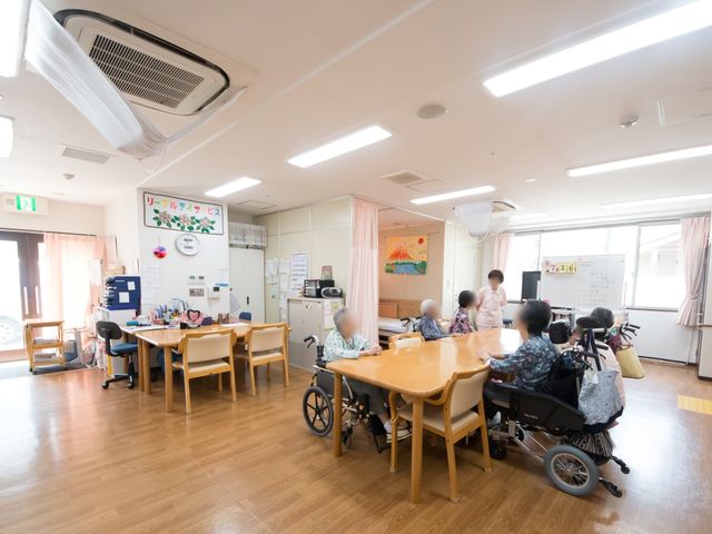 共有スペースでの憩い 談話室 ゆったりとした食事スペースで、利用者の方々が会話を楽しんでいます。明るい採光と清潔感のある環境で働ける場所です。