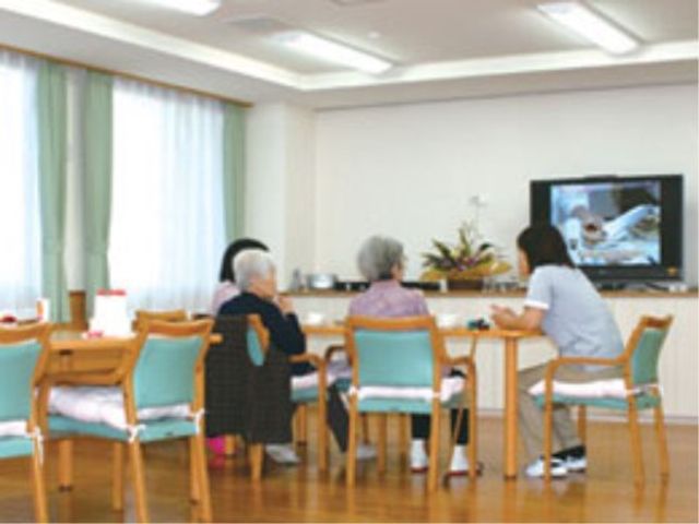 共用スペースでの憩いの時 談話室 明るく開放的な食堂で、皆さんがテレビを見ながら憩いの時間を過ごしています。ゆったりとした椅子が配置され、心地よい空間が保たれています。