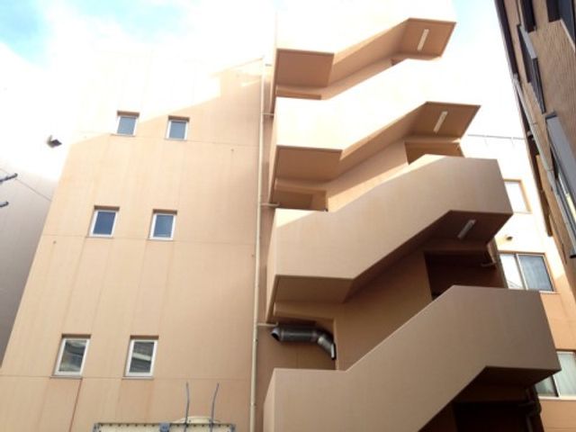 ベージュの外壁の建物外観 外観2 モダンなデザインの建物で、落ち着いた色合いが周辺の景観に調和しています。