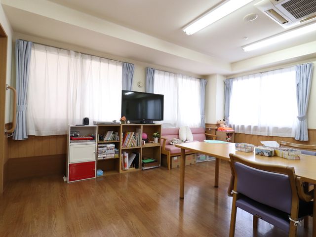 広々とした明るい居室 テレビとソファ ゆったりとした雰囲気の居室で、大型テレビや読書が楽しめます。窓からは自然光があふれ、快適な生活空間を提供しております。