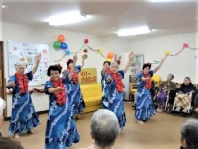 盛り上がるレクリエーション レクリエーション カラフルな衣装に身を包み、手にはポンポンを持った笑顔あふれるイベントの様子です。見守る人々の和やかな雰囲気も伝わります。