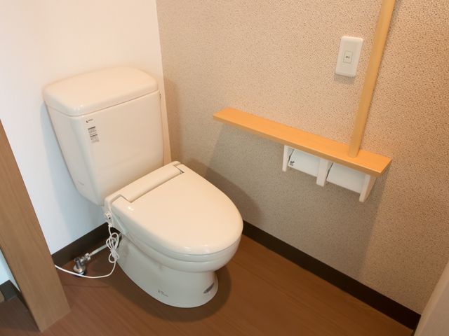 バリアフリー設計のトイレ トイレ 手すり付きで安全に配慮された清潔なトイレ空間です。快適にお過ごしいただける環境が整っています。
