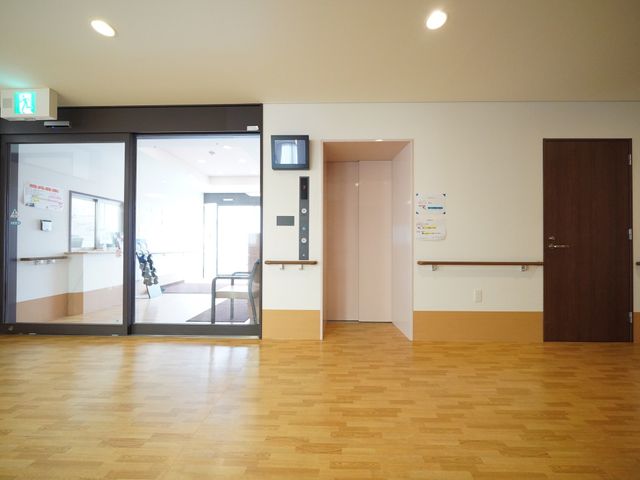 床が明るい廊下の一角 エントランス ゆったりとした廊下は、天井の高さと床の木目調が開放感を与え、快適な移動空間を提供しています。明るく清潔感のある環境です。
