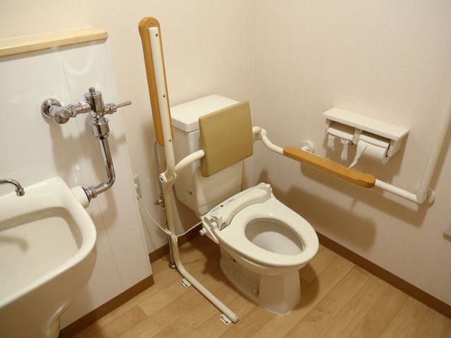 手すり付きの清潔なトイレ トイレ 機能性に優れた手すりが設置されたトイレです。利用者の安全と自立を支える設計が行き届いています。