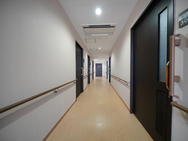 明るく清潔な廊下 通路 手すりが設置された広々とした廊下です。落ち着いた色調で、心地よい勤務環境が整っています。