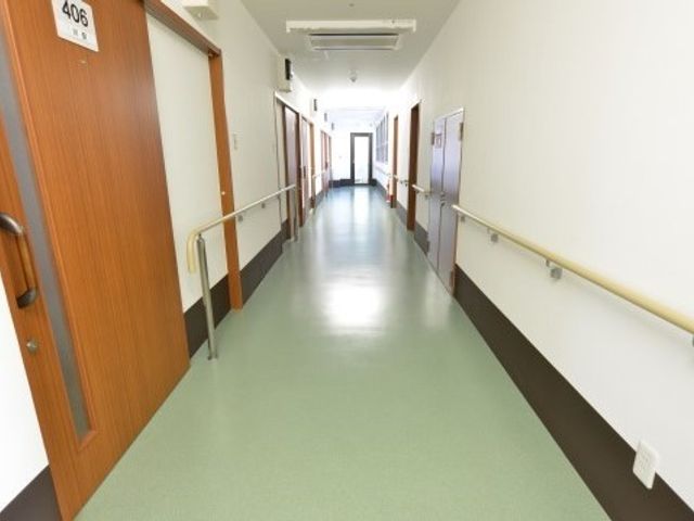 清潔な施設の廊下 廊下 ゆったりとした廊下は清潔感があり、手すりが設置されていて安全に配慮されています。落ち着いた色合いが心地よい空間を提供しています。