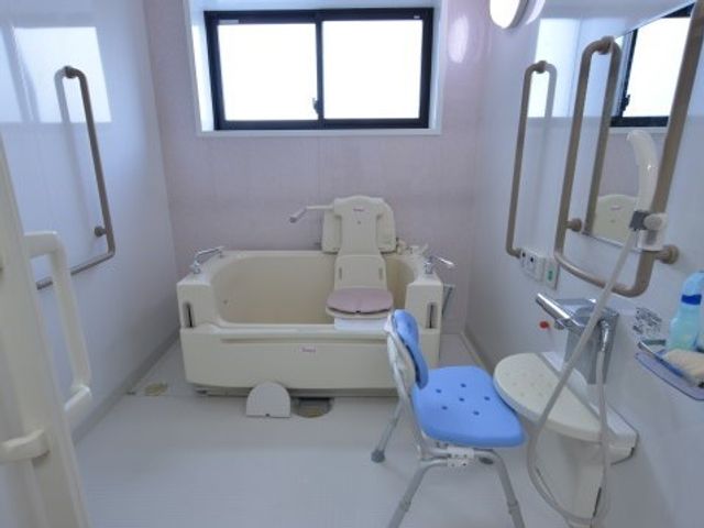バリアフリー設計の浴室 機械浴設備 清潔で広々とした浴室は、利用者の方々の身体的な負担を減らし、安全な入浴を支援しています。手すりやシャワーチェアも完備され、快適性と機能性を高めています。