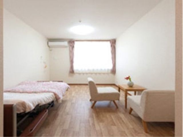 居室の明るい室内 居室 広々とした居室は木目調で落ち着いた雰囲気です。窓からは自然光が差し込み、ゆったりとした時間を過ごせる空間が広がっています。