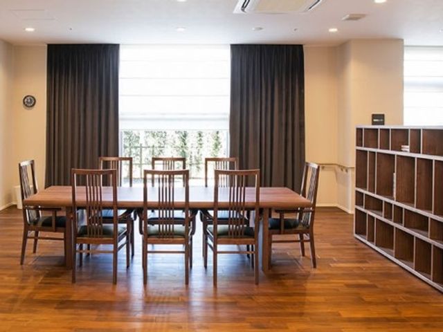 木製のテーブルと椅子が置かれた部屋 共有スペース ゆったりと配置されたダイニングセットが、共に食事を楽しむ温かな雰囲気を醸し出しています。