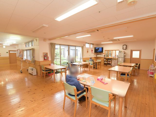 共有スペースと滞在者 リビング 暖色系の壁と木目調の床が温かみのある共有スペースです。複数の方がくつろぎながら、交流を深めることができます。