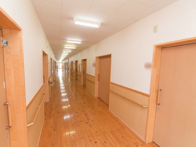 明るい木目調の廊下 廊下 木の温もりが感じられる廊下は、広々として歩くのも快適です。ゆとりある設計は、働く環境にも配慮されています。