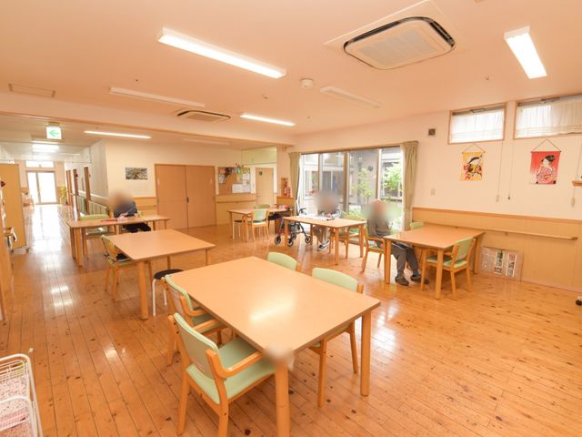 明るい居室の様子 リビング 広々とした木のぬくもりを感じる居室で、ご入居者がリラックスしながら過ごしています。ゆったりとしたスペースで日々の生活がイメージできます。