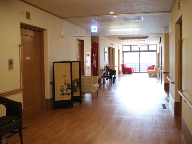 暖かい雰囲気の廊下 廊下 広々とした廊下には、レッドのソファが配され、待ち時間も心地よく過ごせます。手すりが設置されており、安全に配慮された設計です。