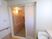 引き戸の浴室の扉である。脱衣室の壁は白で統一され、清潔感に溢れている。壁にはてすりが取りつけられている。