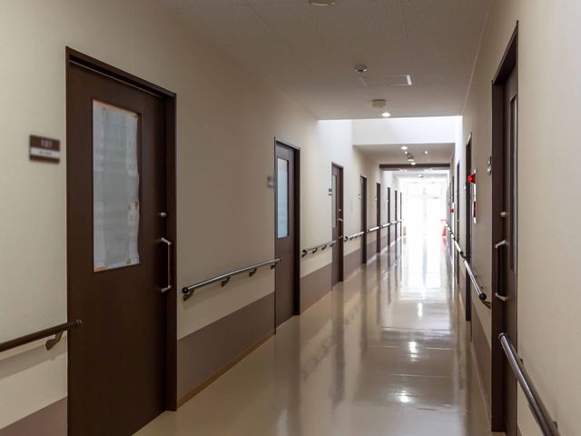 明るい廊下の風景 廊下 手すりが設置された清潔感のある廊下です。利用者の安全な移動をサポートするための配慮が見受けられます。