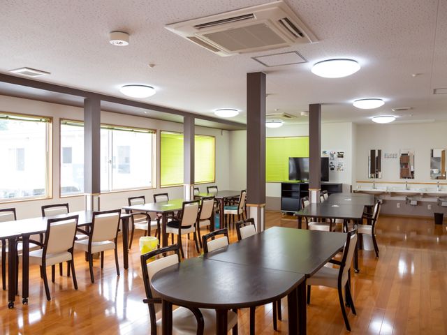 広々とした明るい食堂 共有スペース 広々とした食堂は明るく清潔感があり、共に食事を楽しむ快適な空間を提供しております。木目調のテーブルと椅子が温かみを感じさせ、リラックスできる環境です。