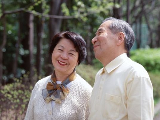 老夫婦が笑顔で外に立つ