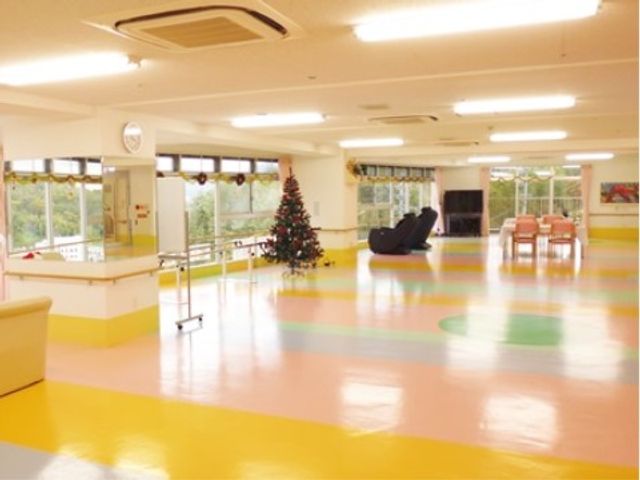 広々とした明るい機能訓練室 ホール 床がカラフルで明るい雰囲気の機能訓練室です。クリスマスツリーが置かれ、季節感も感じられる空間となっています。