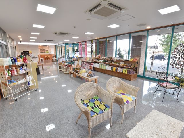 売店前の休憩スペース 売店 ソファに清潔感あるカバーがかかっており、売店の隣でくつろげる空間が設けられています。明るく開放的な雰囲気の中、来訪者やスタッフがくつろぐ姿が想像できます。