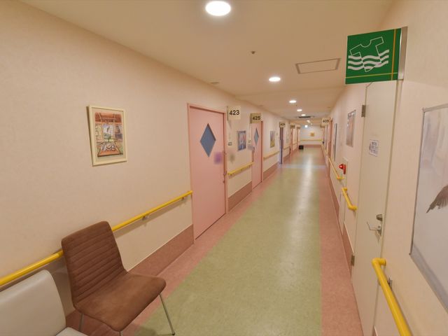 廊下の明るいイメージ 通路 ゆったりとした空間の廊下は、掲示物やアートが飾られ、暖かな雰囲気に包まれています。手すりも設置され、安全に配慮された設計となっております。