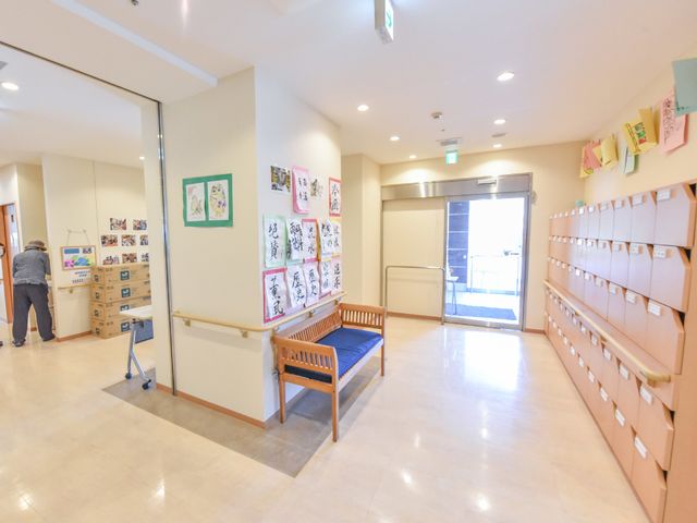 廊下の掲示物と郵便受け 廊下 ゆとりのある廊下には、暮らしを彩る掲示物が飾られ、快適な通行が可能です。郵便受けの整然とした配置も見受けられます。