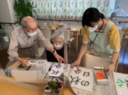書道を楽しむ利用者とスタッフ