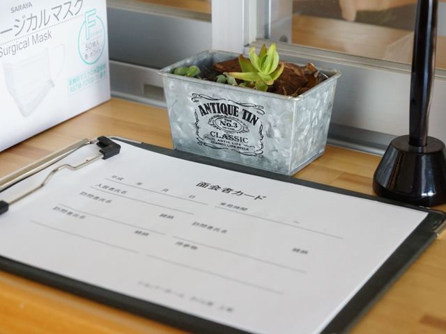 受付台のクリップボードと植物 受付 丁寧に整頓された受付エリアです。訪れる方々が快適に手続きを進められるよう配慮されています。