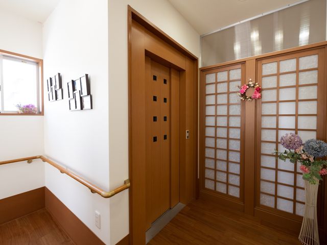 廊下の洋風スライド扉 エレベーター おしゃれな装飾とスライド扉が心温まる廊下です。手すり付きで安心して歩行ができる設計になっています。
