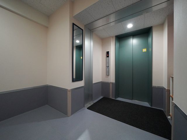 清潔な廊下とエレベーター エレベーターホール 清潔感溢れるスペースには、利用者が安心して移動できるよう設計されたエレベーターが設置されています。