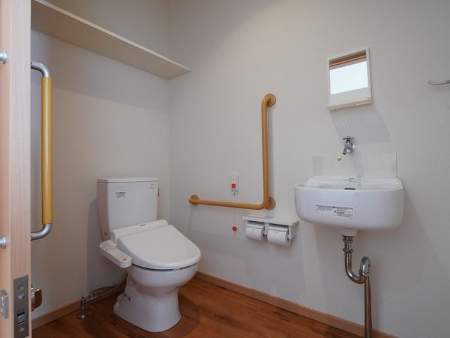 手すり付きのトイレ トイレ 手すりや緊急コールが整った清潔なトイレです。利用しやすい環境が提供されており、安全性も考慮されています。