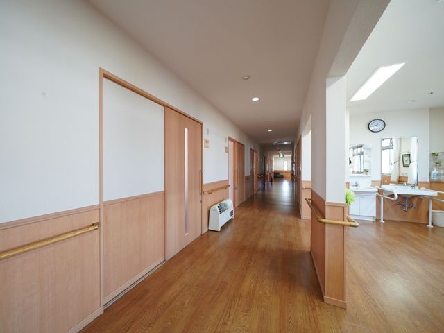 明るい床の廊下 廊下 木目の床が温かみを感じさせる廊下です。手すりが整備されており、安全に歩行できる設計になっています。