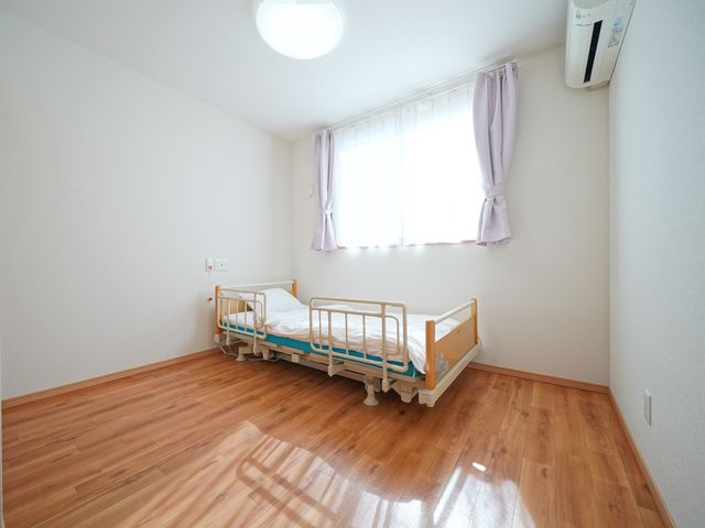 明るく清潔な単身居室 居室 窓から自然光が差し込む、ゆったりとした個室です。快適な毎日をサポートする機能的なベッドが配置されています。