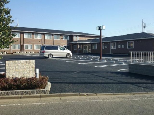 広々とした駐車場と施設 外観 駐車スペースが充実した、快適なアクセスの施設外観です。清潔感のある建物で、安心して働ける環境を提供しています。