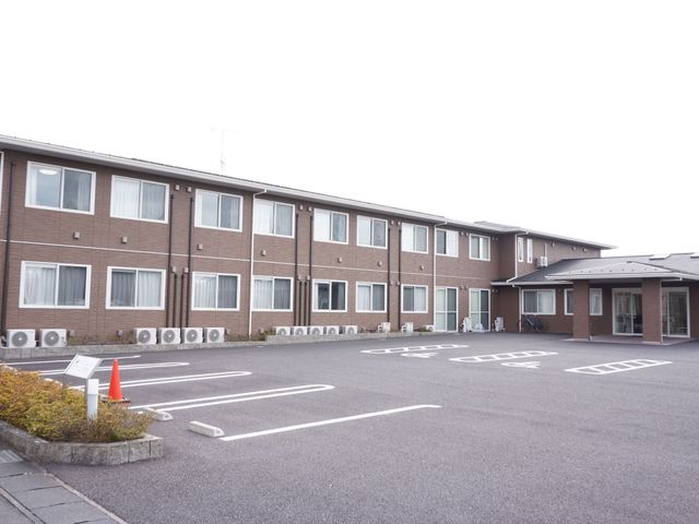 広々とした駐車場の外観 外観 ゆったりとした敷地に建つ、入口が見える建物です。清潔感のある外観が心地よい職場環境を予感させます。