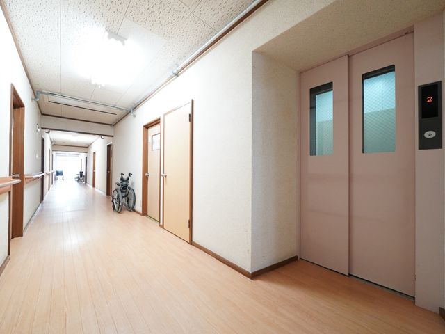 明るい廊下の一角 エレベーター 手すりがついた廊下は清潔感があり、車椅子を置くスペースも十分に確保されています。安全に配慮した設計になっており、すべての方が快適に移動できるようになっています。