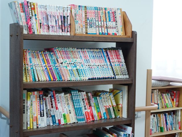 本棚に並ぶ多彩な書籍 共有スペース 色とりどりの書籍が所狭しと並べられた、居心地の良い読書スペースです。利用者の方々にとって心の潤いとなる場所で、新しい発見もあります。