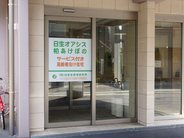 明るい施設のエントランス 入り口付近 広く清潔感のあるエントランスは、訪れるすべての方に開放的な印象を与えます。日中の光が差し込む心地よい空間で、新たな職場としてご活躍いただけます。