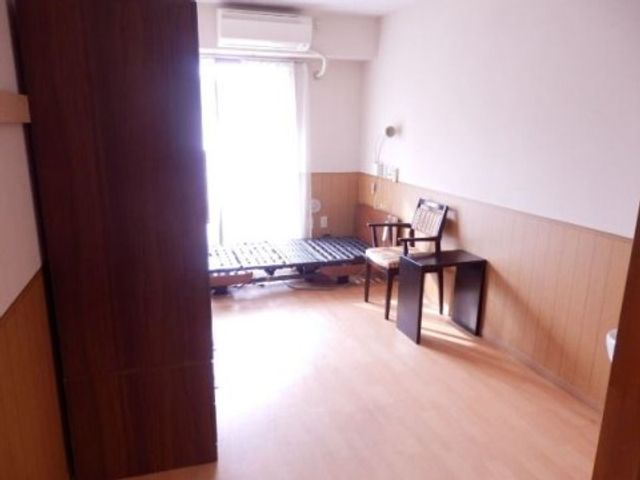 明るい個室の居室空間 居室2 ゆとりのある個室で、大きな窓から自然光が差し込む快適な空間です。安らぐ時間を過ごせるようなシンプルで機能的な家具が配置されています。