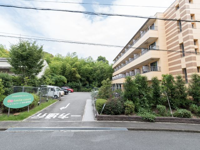 明るい外観の建物エントランス 外観 緑に囲まれた建物の入口です。清潔感のある外観が印象的で、安心してお迎えできる環境が整っています。