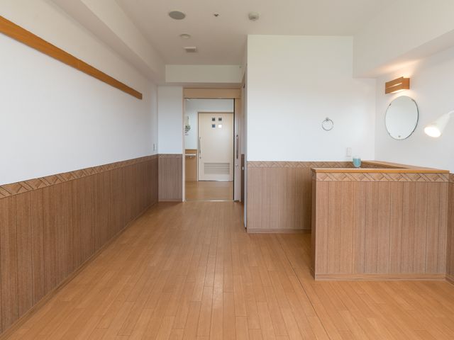 明るく清潔感のある廊下 個室 手すりが設けられた広々とした通路です。明るい雰囲気で、清潔感を感じる環境が整っています。