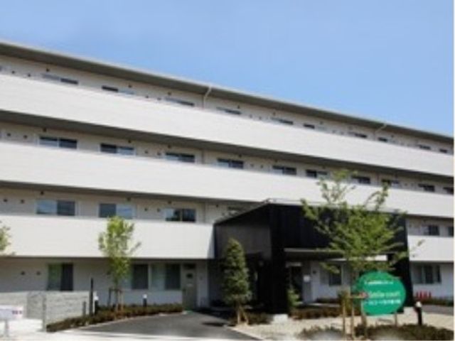 白い壁の施設外観 外観 清潔感のあふれる外観です。みどり豊かな環境が、明るい職場を印象づけています。