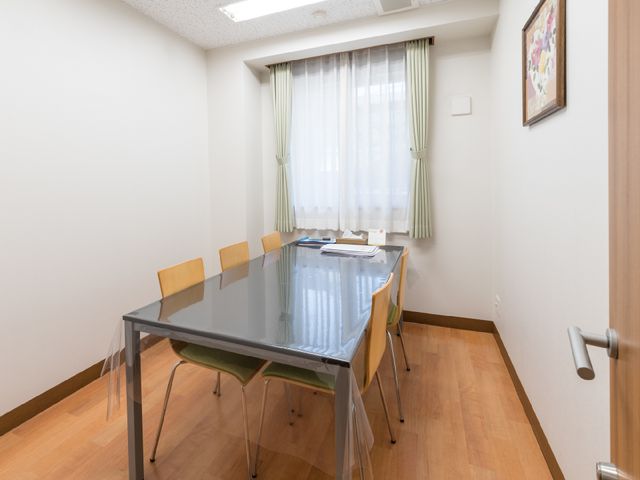 清潔な会議室 部屋 落ち着いた色合いの多目的室で、明るい窓際には会議用のテーブルと椅子が整然と配置されています。会議や研修に最適な空間です。