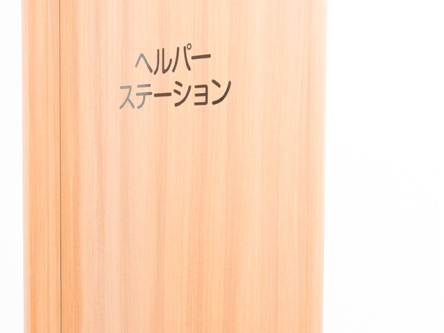 ヘルパーステーション表示板 ヘルパーステーション 温かみのある木目調が印象的なエントランス。日々のサポートが集う場所で、明るい未来を一緒に創造しませんか。