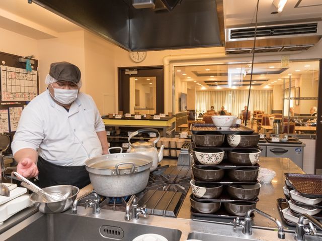 調理スタッフと食堂 厨房 調理を担当するスタッフが、食事の準備に勤しむ広々とした食堂です。皆さんの健康を支える、栄養満点の食事が提供されています。