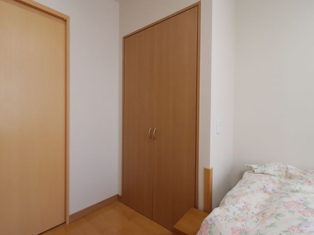 居心地の良い居室の一角 収納 ゆったりとした寝具と木目調の温かみのある扉が印象的な居室で、落ち着いた時間を過ごせる空間です。