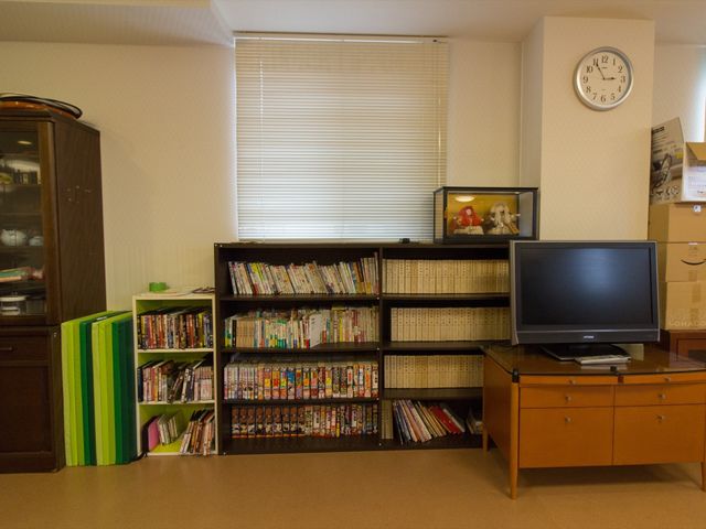 和室のテレビと本棚 デイサービス室 ゆったりとしたリビングの角には、多様な書籍や映像作品が整然と並べられ、心地よい時間を過ごすための環境が整えられています。