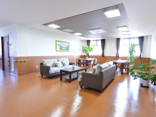 共用ラウンジの明るい空間 談話コーナー 窓から光が差し込むラウンジです。ゆったりとしたソファで、訪問者や利用者の皆様の憩いの場を提供しています。