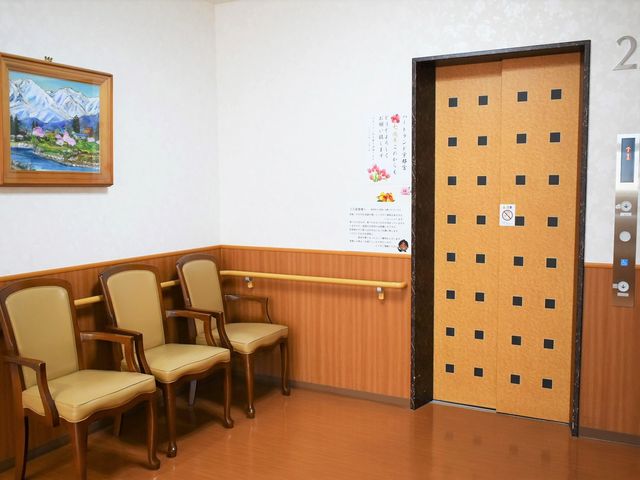清潔感ある廊下の風景 エレベーター 落ち着いた色合いの椅子が並べられた廊下です。壁に飾られた美しい絵画が訪れる人々を暖かく迎えています。