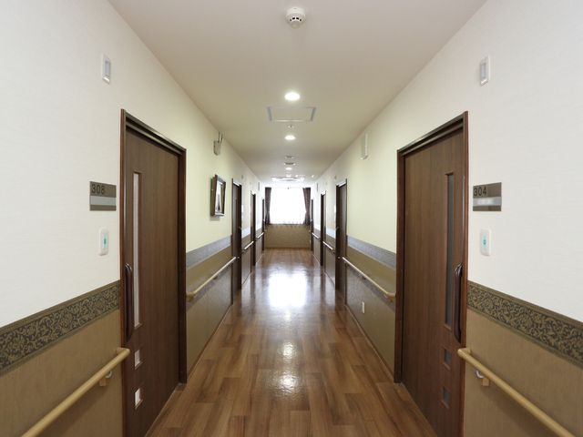 明るい廊下と部屋のドア 廊下 清潔感漂う廊下は明るく、居心地の良さが伺えます。安定した手すりがあるため、歩行が不安な方も安心です。