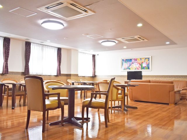 快適な共有スペース 談話室 暖色系の照明と柔らかな色合いの家具が、温もりのある食事のスペースを演出しています。ゆったりとした雰囲気の中でのコミュニケーションも楽しめそうです。